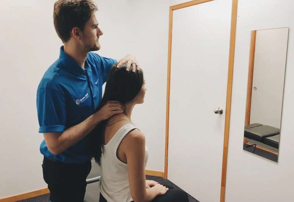 Chiropractor assessing patient's neck at Absolute Health Mooloolaba clinic.