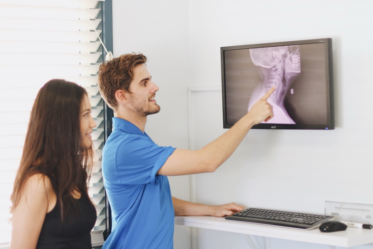 Absolute Health practitioner explaining a neck (cervical spine) X-ray to a patient on screen at the Mooloolaba clinic